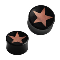 Load image into Gallery viewer, Two black, cylindrical Horn Plug Stern Inlay metallic rosegold schwarz Expanders, handcrafted with flat tops and a metallic rose gold star center. Both flesh tunnels are shown on a white background, one slightly larger than the other.
