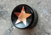Load image into Gallery viewer, A handmade Horn Plug Stern Inlay metallic rosegold schwarz Expander Flesh Tunnel with a shiny rosegold star on black, shown on a gray speckled surface.
