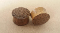 Load image into Gallery viewer, Two round Flesh Plug Teakholz Peace Knoten Muster double flared Lobe Dehner in brown, each engraved with a geometric knot design, rest on a plain light brown surface—ideal for fans of organic piercing jewelry.
