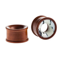 Cargar imagen en el visor de la galería, A pair of hand-carved Holz Tunnel plugs made from rosewood: one showcases a white-brown marbled Howlite inlay with a tribal design, while the other features a solid rosewood surface.
