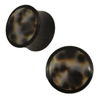 Load image into Gallery viewer, A pair of round Organic Arangholz Plugs with black dots and a white-d dark tribal shell inlay, featuring a smooth, marbled surface.
