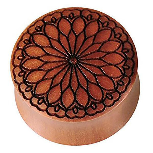 Ein runder Plug aus Sawo Holz in Braun mit schwarzer Gravur im Blüten- und Herz-Tribal-Muster – handgeschnitzt, filigran und organisch als Expander oder Tunnel tragbar.