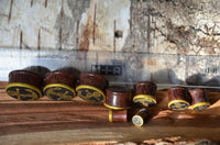 Load image into Gallery viewer, A set of "Plug Holz Tamarinde dunkelbraun Anker Seil Brass Überzug golden Rand" plugs is arranged in a row on wood, with a ruler for scale. Each plug features an anchor design with brass trim and varies in size.
