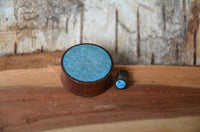 Load image into Gallery viewer, A Holz Plug Sonoholz Crushed Türkis Inlay double flared rests on a wooden surface beside a matching accessory, both highlighted against a rustic, light wooden background.
