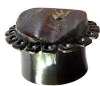 Load image into Gallery viewer, A close-up of the "Horn Plug Blumenform dunkelbraun Rohhorn double flared," featuring a wide, dark brown band with a flat, carved top and decorative holes. The polished surface highlights the natural horn texture.

