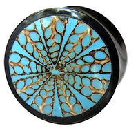 Load image into Gallery viewer, The Horn Plug Spinnennetz blau is a round black plug hand-carved from Büffelhorn, featuring a blue and brown geometric starburst pattern on its face.
