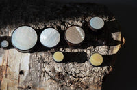 Load image into Gallery viewer, The Holz Plug Perlmutt Inlay Gravur Blume des Lebens ribbed plugs are displayed on textured wood, showcasing their geometric lids with Flower of Life engraving and shimmering inlaid perlmutt under dramatic light and shadow.
