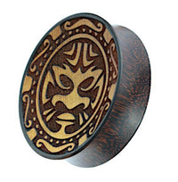 Load image into Gallery viewer, A double flared Plug Holz hell dunkel features a Tribal Maske engraving on top with a decorative border, while the sides display the natural wood grain, making this unique Holzplug both stylish and distinctive.
