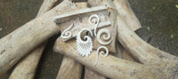 Cargar imagen en el visor de la galería, The Bone HornTunnel weiß schwarz gestreift double flared, featuring white and black stripes, is crafted from organic bone and buffalo horn and displayed atop large ivory tusks on a concrete surface.
