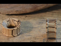 Load image into Gallery viewer, Two Bananenholz Flesh Tunnel hell ribbed straight konkav plugs display natural light and dark grain patterns on a textured wood surface; one lies flat, one stands upright near a ruler for scale—unique jewelry pieces.
