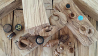 Load image into Gallery viewer, Discover the Plug Olivenholz Pin-Creole: a handcrafted brown marbled wood pin-creole displayed on natural wood. It features unique shapes, colorful stone inlays, and symbolic designs, perfect for fans of artisan jewelry.

