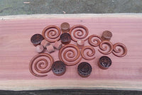 Load image into Gallery viewer, A collection of wooden ear gauges, including Rosenholz Dehnschnecke Spirale Ohr Piercing in reddish-brown, displayed on a smooth light-pink wooden surface for organic piercing enthusiasts.
