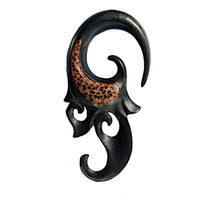 Load image into Gallery viewer, The Holz Piercing schwarz Eizenholz Spirale features a black, curved tribal ear gauge with a swirling design and brown Kokosholz Inlay, inspired by Dehnschnecke styles, shown on a white background.
