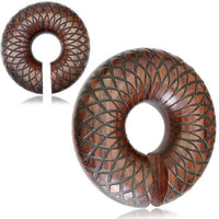 Load image into Gallery viewer, A close-up shows a wooden Ohr Donut Piercing Dahlie Holz Ohrgewicht Ring puzzle piece with a geometric checkered pattern and a slot on one side, while another similar item appears in the background.
