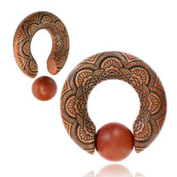 Load image into Gallery viewer, Two circular Captive Bead Klemmkugel Ring Sawoholz Piercing Mandala ear weights in brown wood, featuring black floral carvings and a smooth wooden bead between the open ends, are displayed on a white background.
