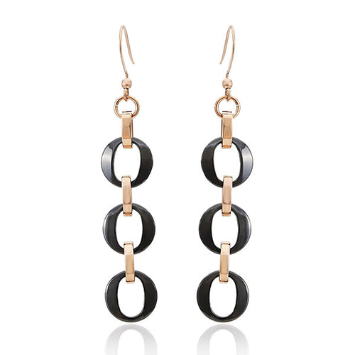 These Ohrringe Ohrhänger Damen aus Edelstahl und Keramik bestehen aus drei schwarzen ovalen Ringen, verbunden mit goldfarbenen Elementen und nickelfreien Haken für angenehmen, rostfreien Tragekomfort.