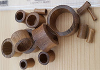 Load image into Gallery viewer, A selection of Teakholz Flesh Tunnel braun double flared Plugs in various sizes is scattered on a light wooden surface, with a ruler partially visible at the top for scale.
