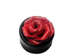 Load image into Gallery viewer, A black round container displays the Leder Holz Plug schwarz Sonoholz—a detailed, red, rose-shaped, tribal tunnel unisex earring, perfect for lobe piercing fans.
